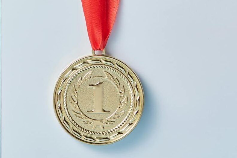 Gold and silver medals with red ribbons against a blue backdrop representing achievement and success.